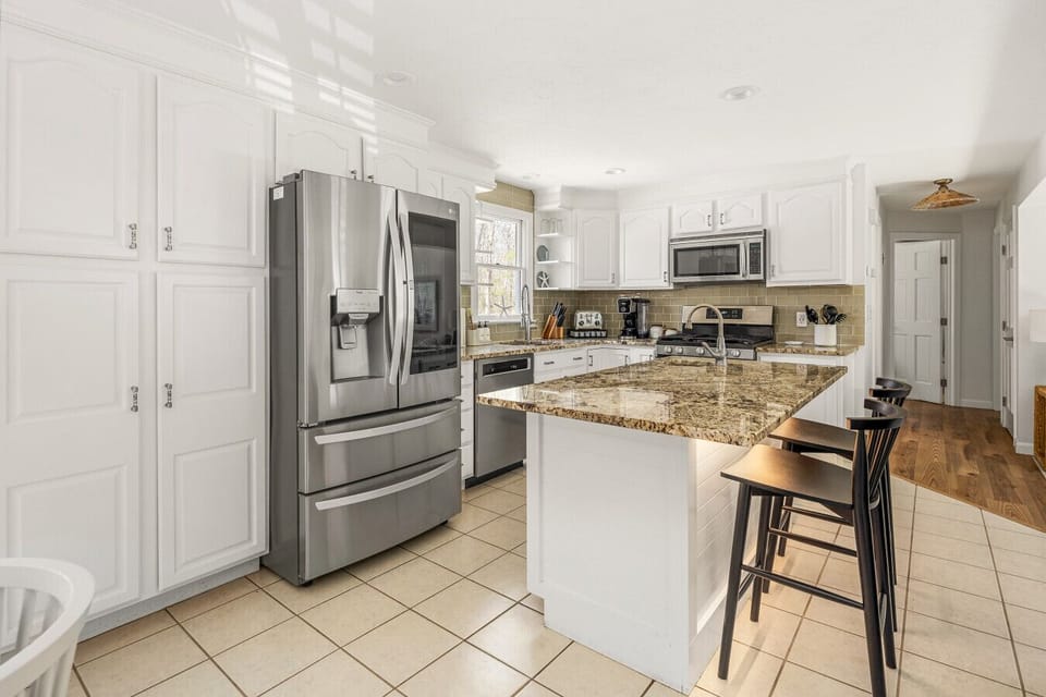 Enjoy this fully stocked kitchen with stainless steel appliances, granite countertops, and a convenient kitchen island with seating.