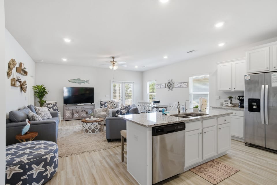 Gather in your spacious open-concept living area where modern coastal style meets comfort—perfect for preparing meals together and relaxing.