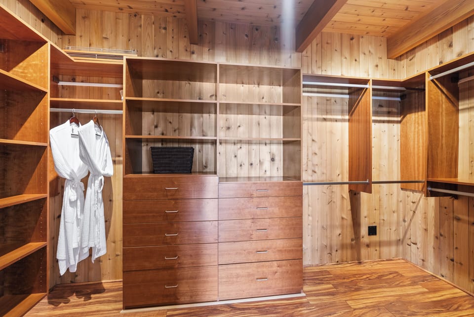 The spacious walk-in closet offers custom wood cabinetry, generous storage, and thoughtful organization for effortless extended stays.