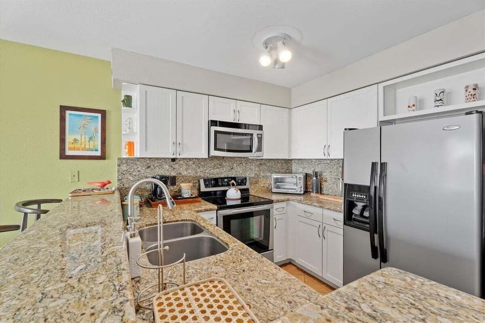 Modern coastal kitchen featuring granite counters, stainless steel appliances, double sink, and ample cabinet storage.