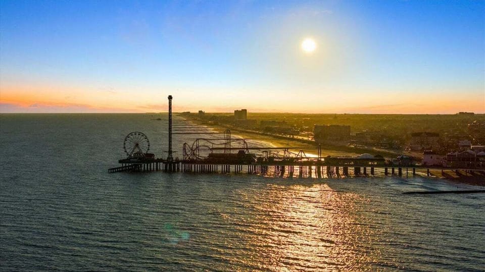 Sunset view over the water with pier scenery and golden coastal Galveston horizon.