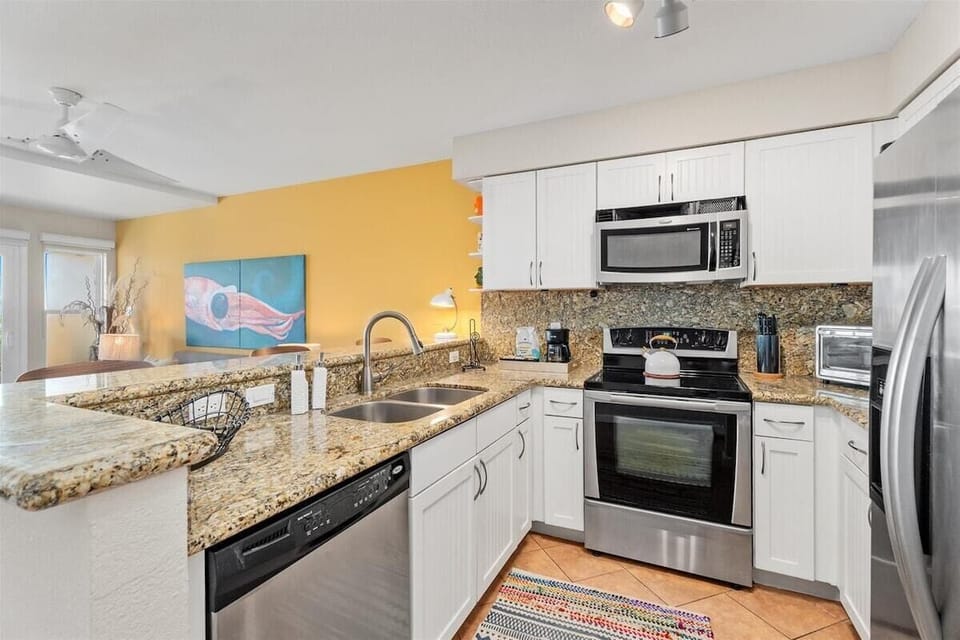 Full kitchen with stainless oven, microwave, dishwasher, granite counters, and tile backsplash.