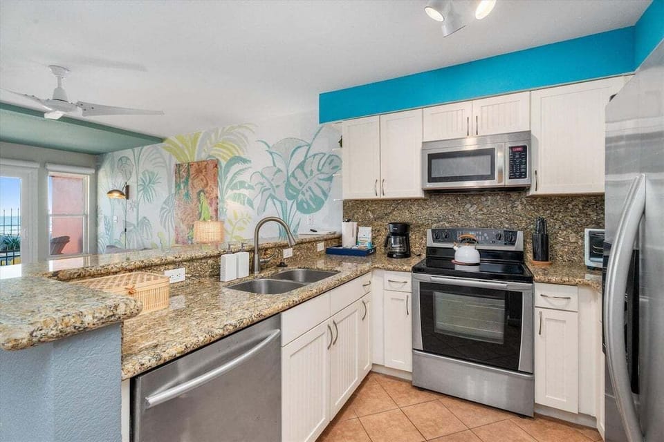 Modern kitchen featuring stainless steel appliances, granite countertops, double sink, and generous prep space for convenient meal preparation.