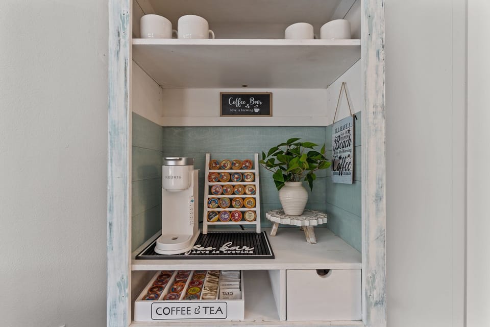 Charming Oak Island NC coffee bar featuring a Keurig coffee maker, K-cup selection, mugs, and tea station, creating the perfect spot to start your morning before heading to the beach.