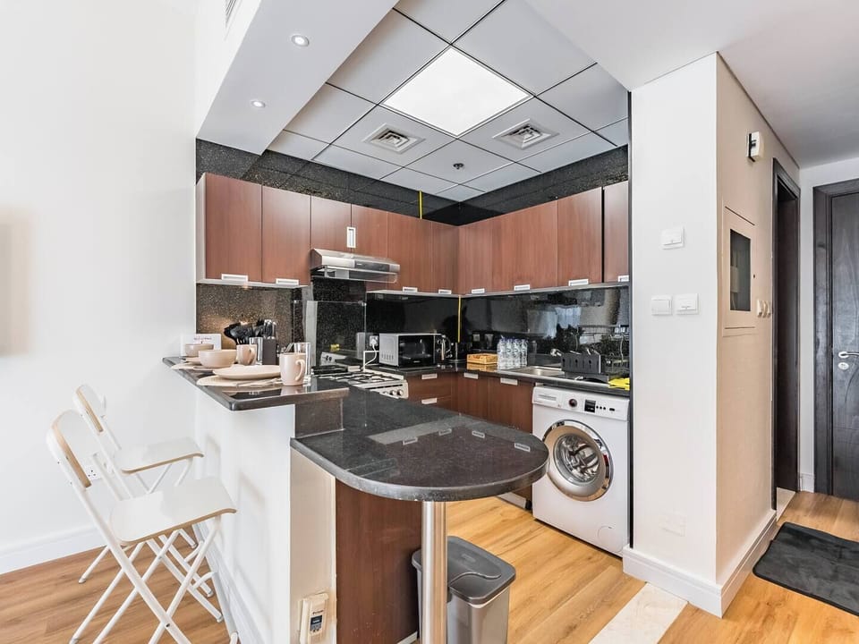 Modern kitchen with granite countertops, wooden cabinets, full appliances, and a breakfast bar with seating—stylish and functional.