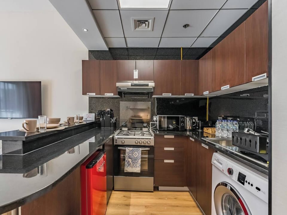 Sleek kitchen equipped with granite surfaces, wooden cupboards, complete appliances, and a bar-style dining area—modern and efficient.