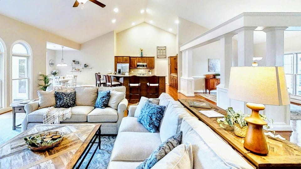 Indulge in a spacious and elegantly designed lakefront retreat, featuring cozy seating, high ceilings, and a seamless open floor plan perfect for gatherings.