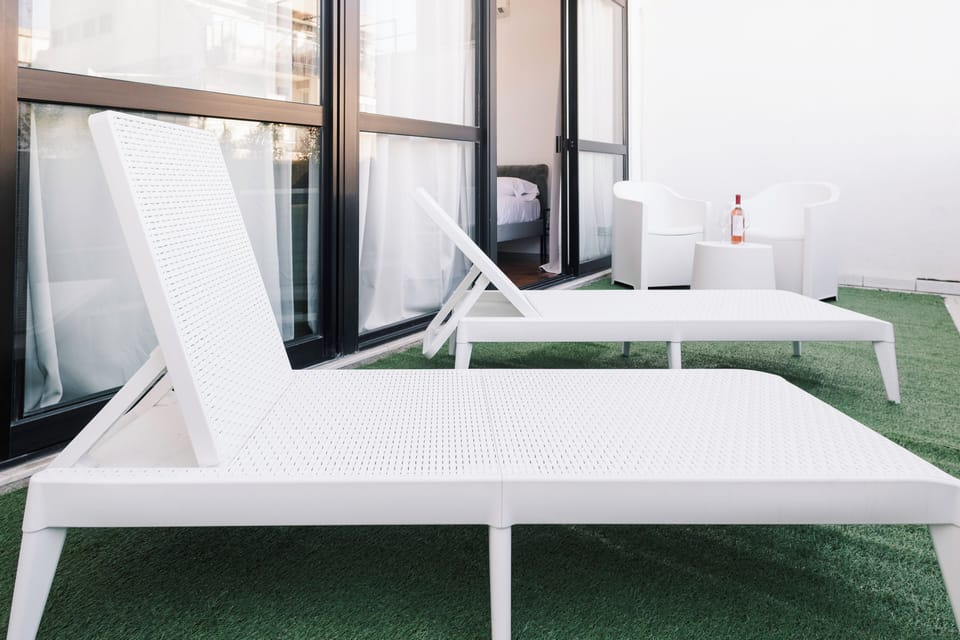 Ampia veranda luminosa con due lettini prendisole, due poltroncine e tavolino.