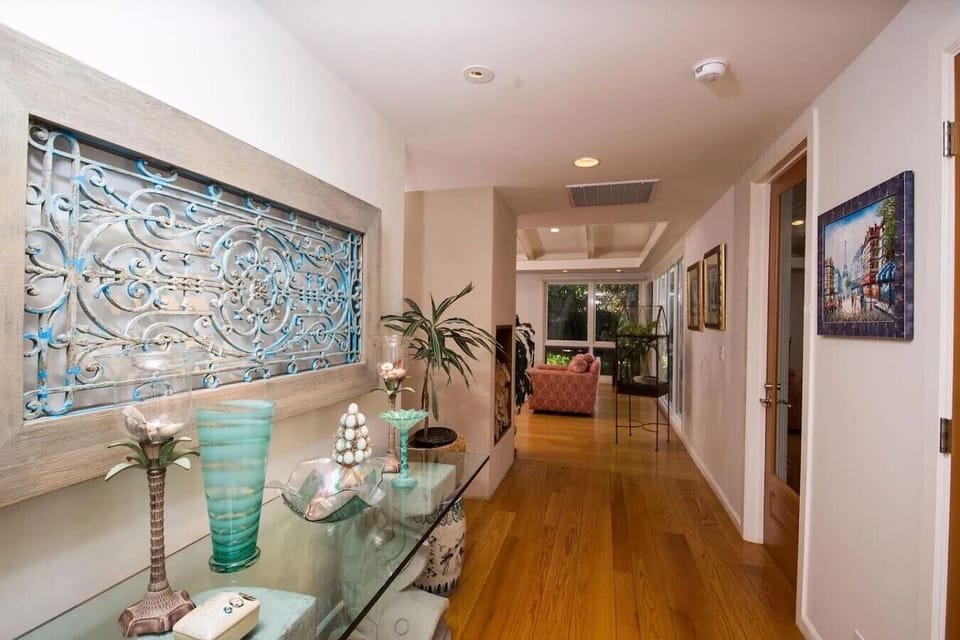 Elegant hallway with hardwood floors, coastal-inspired decor, and curated accent pieces. This bright and inviting corridor adds warmth and character to the home's interior design, leading seamlessly into the living area