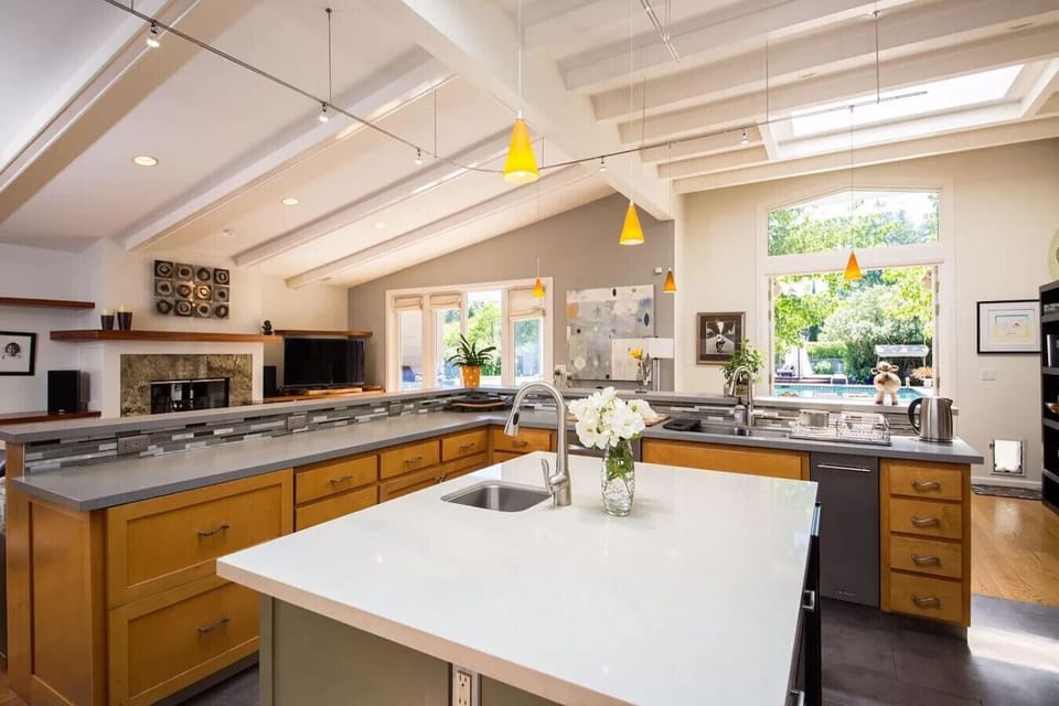 Bright and expansive kitchen featuring a large central island with quartz countertops, vaulted ceilings, modern pendant lighting, and abundant cabinetry. Designed for both functionality and style, this open-concept kitchen is perfect for cooking, entertai