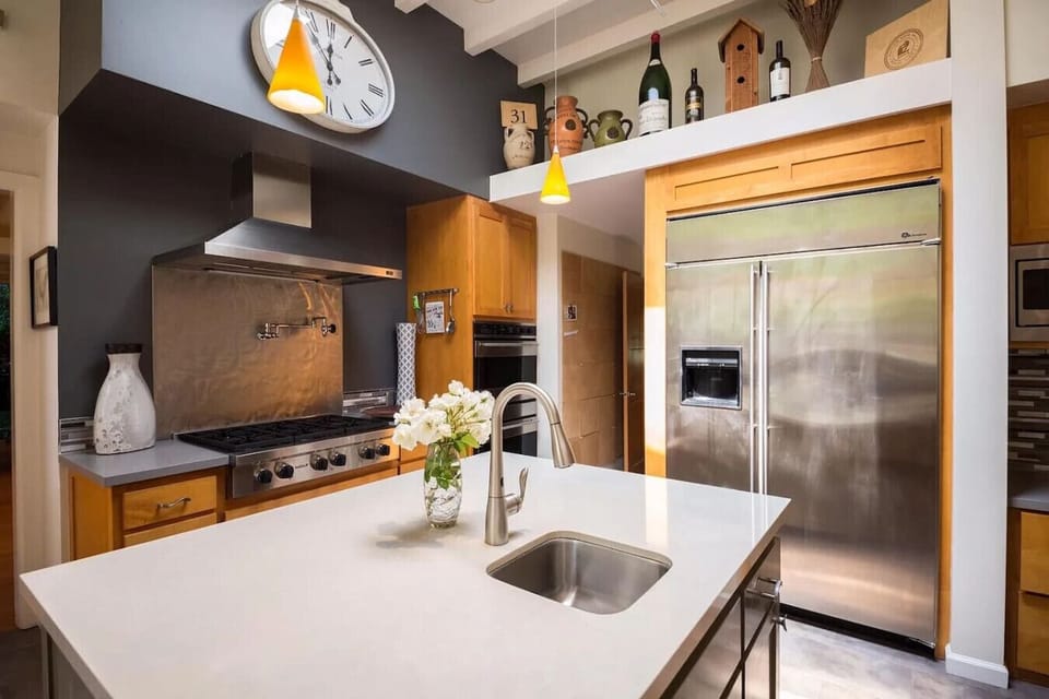 Bright and expansive kitchen featuring a large central island with quartz countertops, vaulted ceilings, modern pendant lighting, and abundant cabinetry. Designed for both functionality and style, this open-concept kitchen is perfect for cooking, entertai