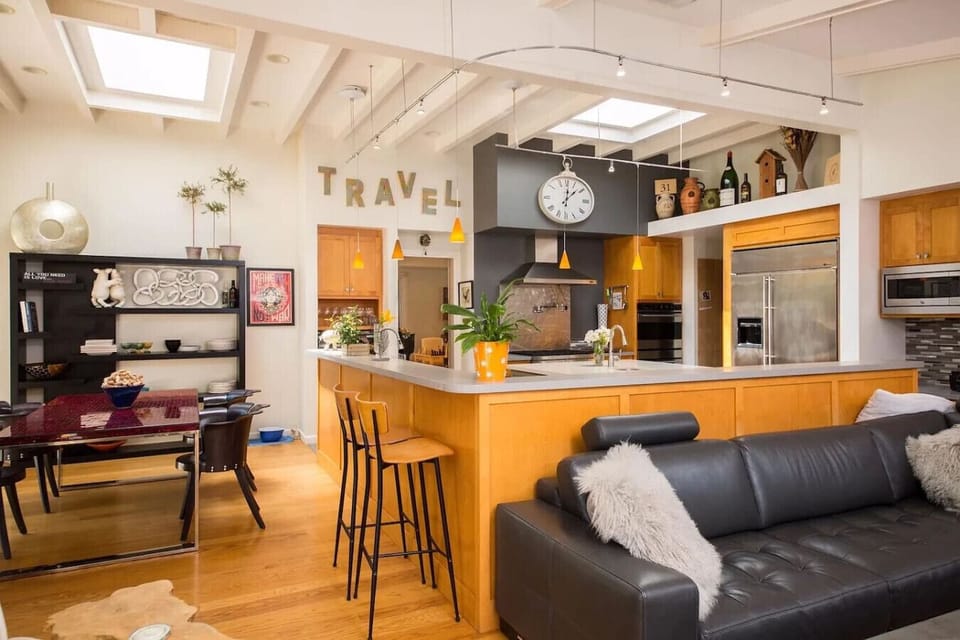 Stylish open-concept kitchen with skylights, stainless steel appliances, bar seating, and a cozy lounge area. Perfect for entertaining or relaxing in a modern yet inviting space.