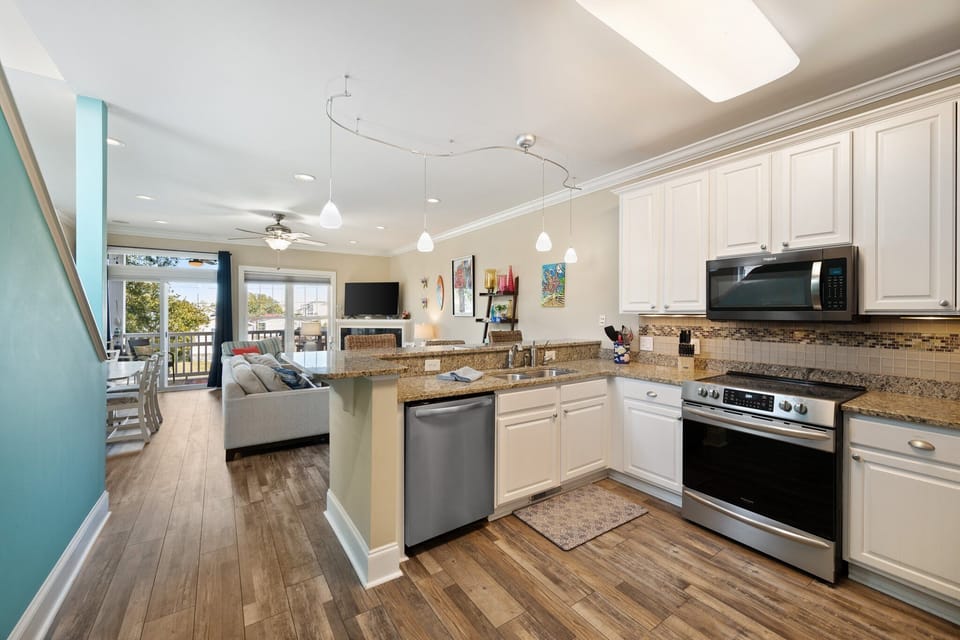 Your stylish open-concept space blends kitchen and living area with granite counters, stainless appliances, and natural light streaming through the balcony doors.