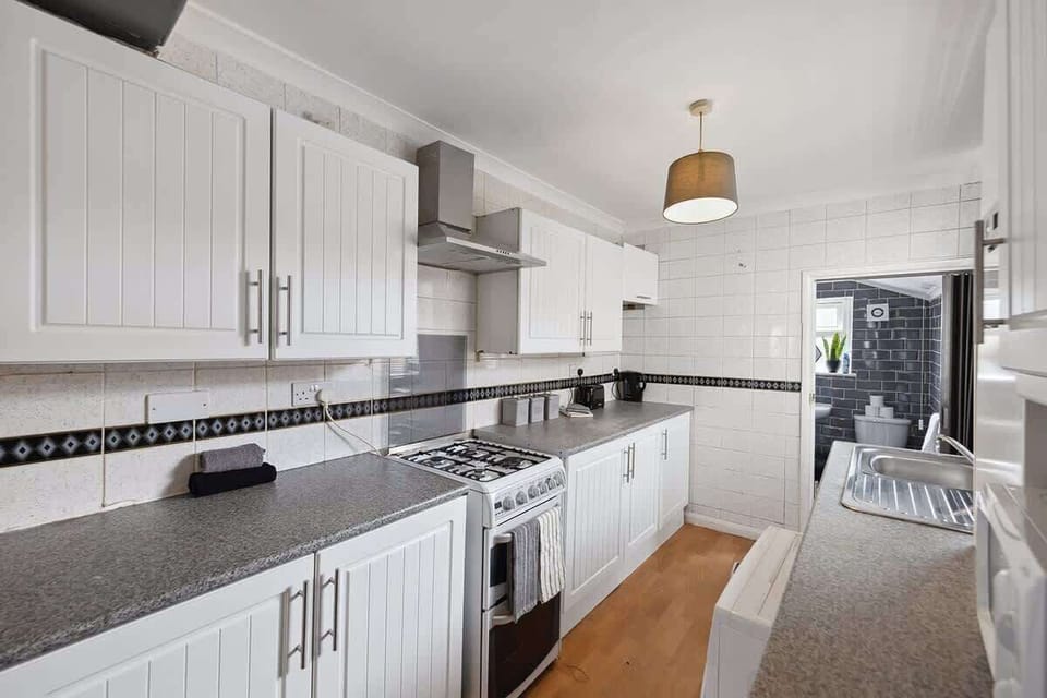 A kitchen equipped with a kettle, toaster, and stove for all your cooking needs.
