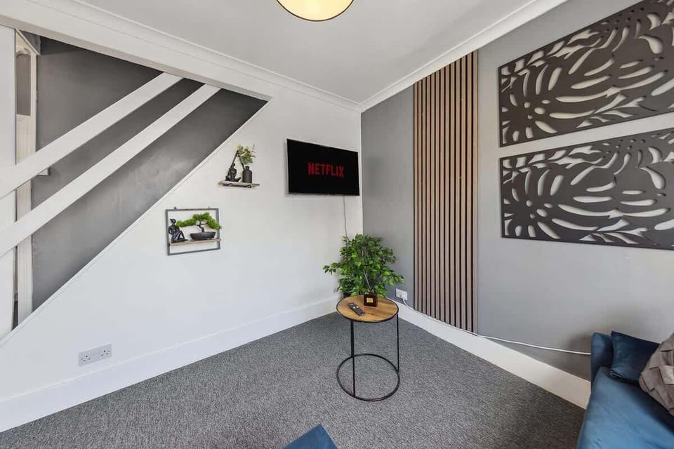 A living room with comfortable sofas, a TV with Netflix, and green decorations for a refreshing atmosphere.
