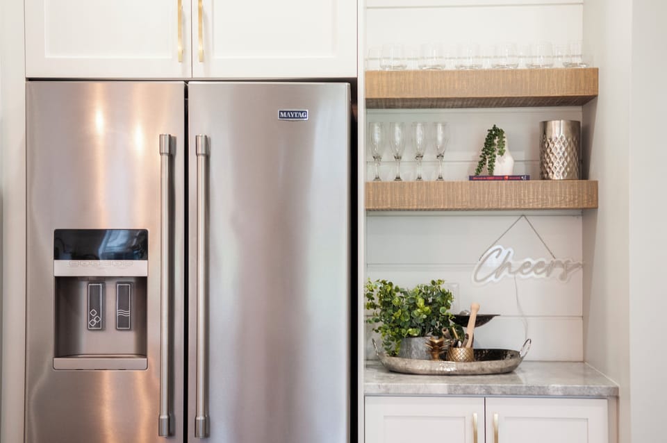 Fridge with ice maker & water dispenser, cocktail area, bar tools and glasses.