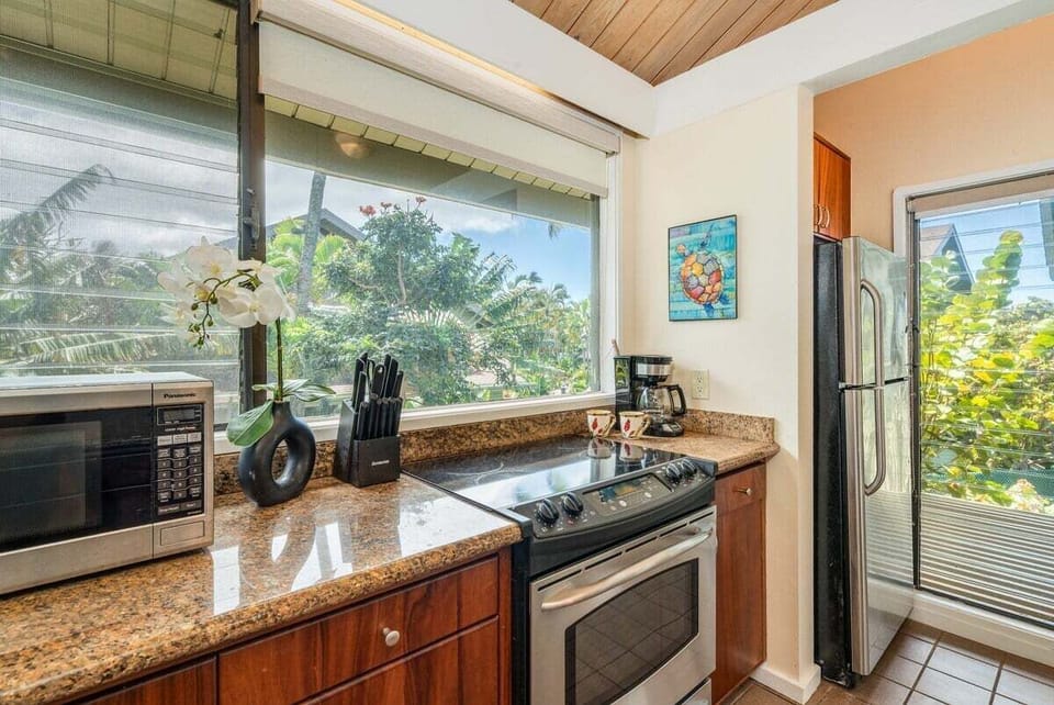 Fully equipped kitchen with stainless steel appliances, granite countertops, and tropical garden views