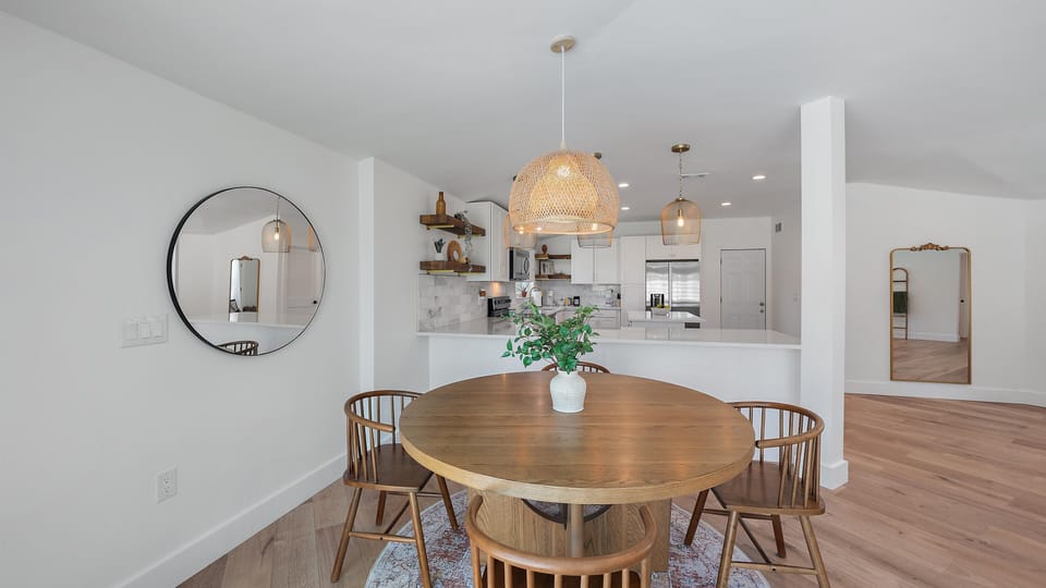 Enjoy group meals and games at the stylish dining table, featuring beautiful coastal decor lighting and an open view into the high-end kitchen.