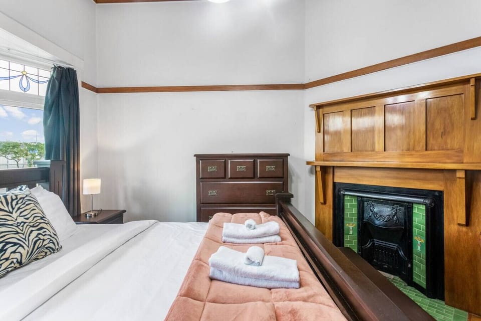The original fireplace dominates the bedroom space with its art deco tiles and wooden mantle.