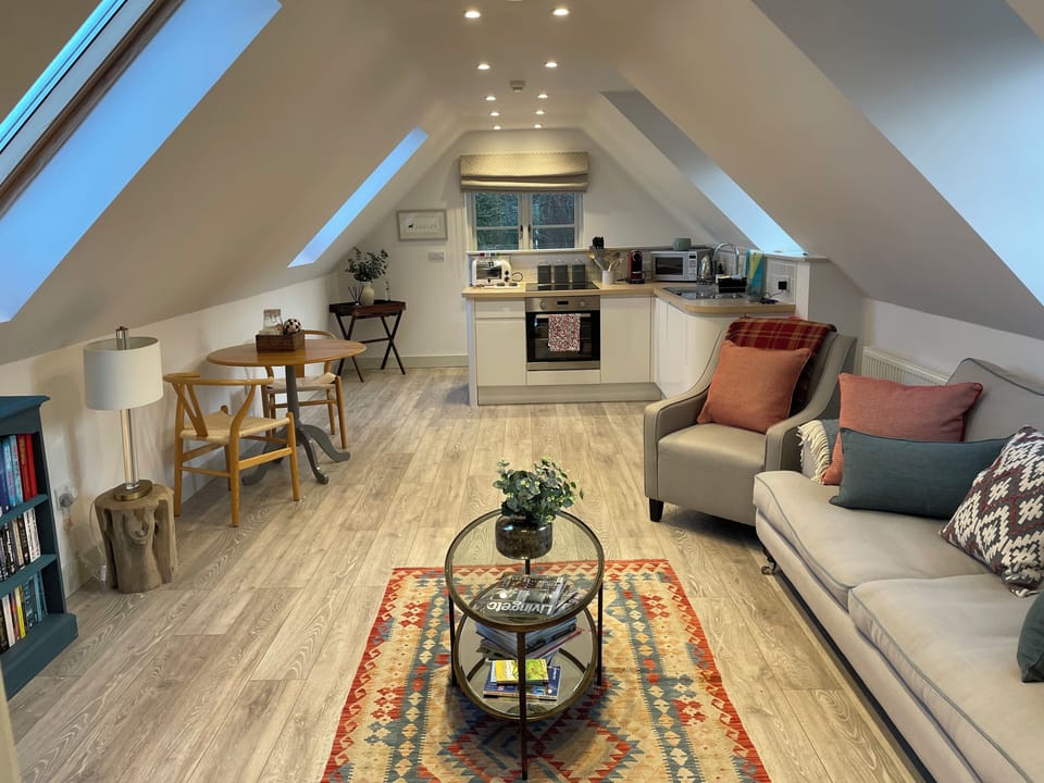 Cosy living area includes comfortable sofa, armchair and dining table for two. 