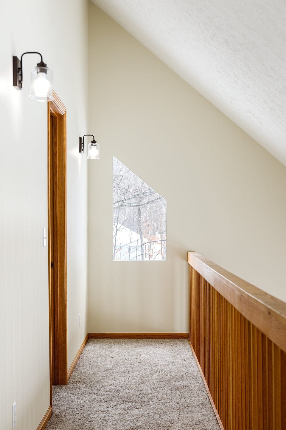 Stair landing w/ wood railing & window views brings in soft natural light.