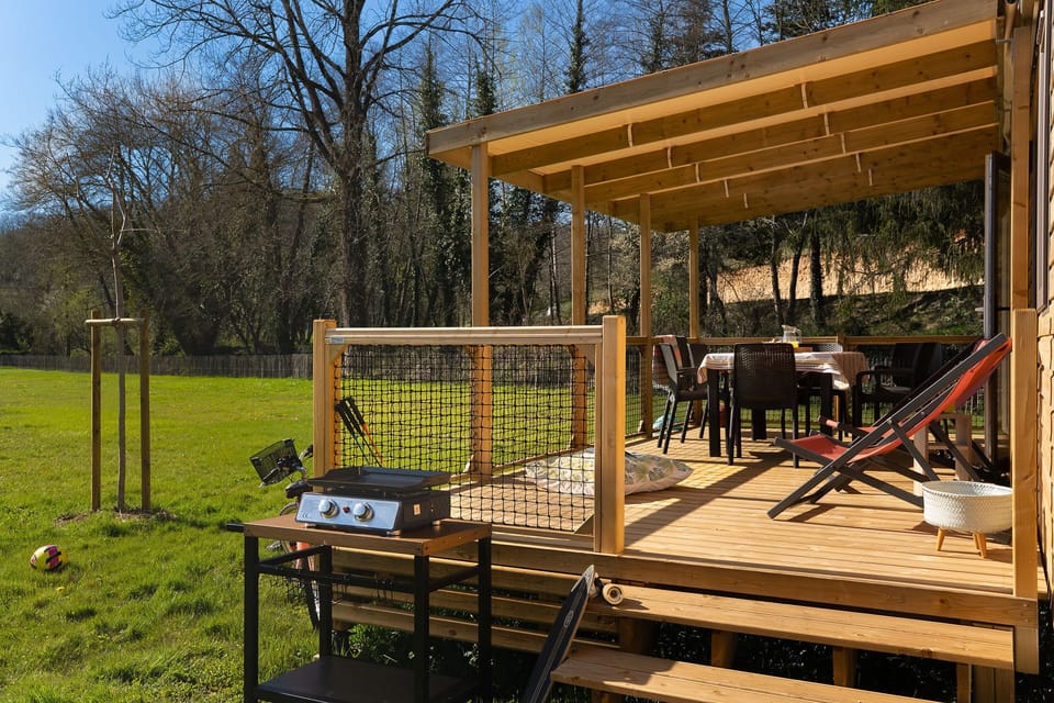 An inviting deck equipped with dining space and a grill creates the perfect setting for outdoor family barbecues and relaxation in nature.