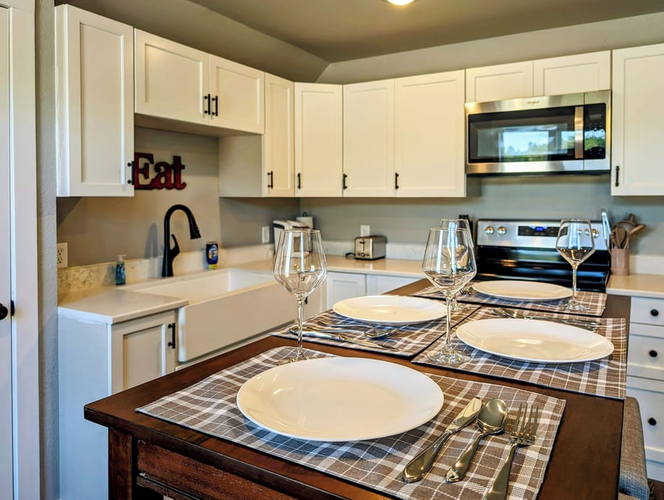 Pub-style table next to a full kitchen with new stainless steel appliances