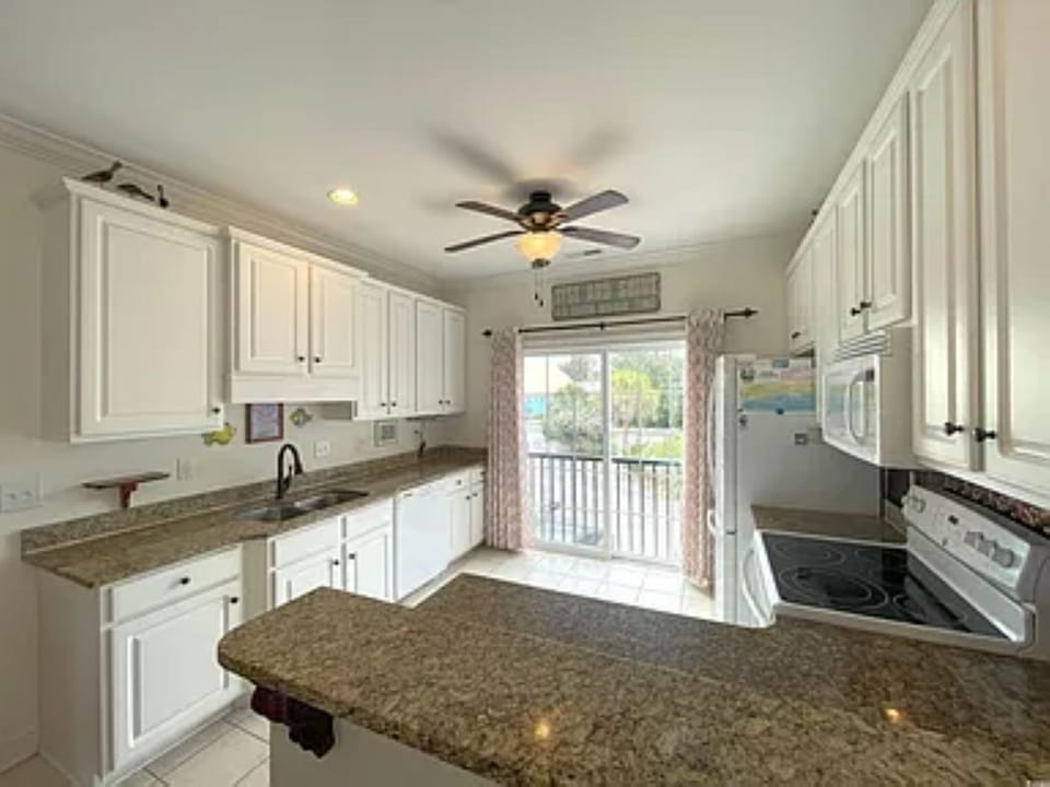 Open kitchen with bar seating and ceiling fan above.