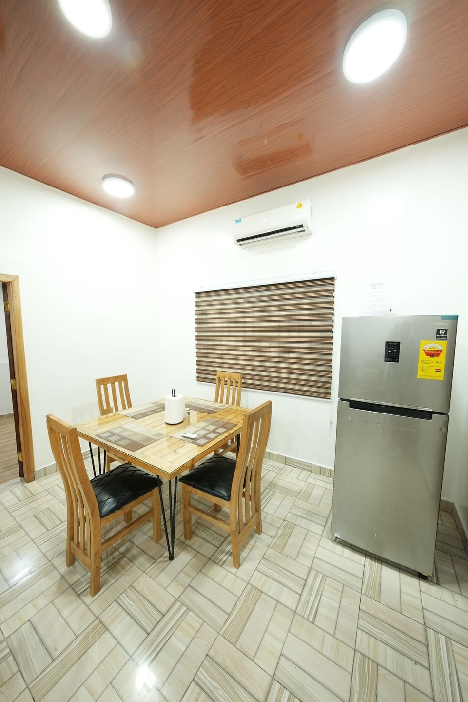 Dining area with wooden table for four, comfortable chairs and air conditioning.