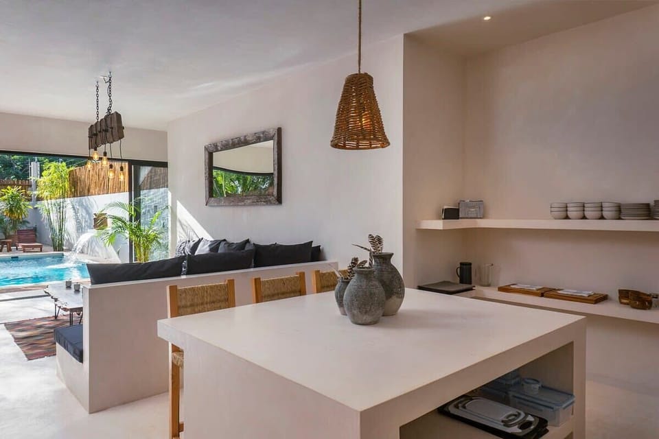 Fully equipped kitchen with a view of the living room and patio. Impressive modern design island with space for three guests