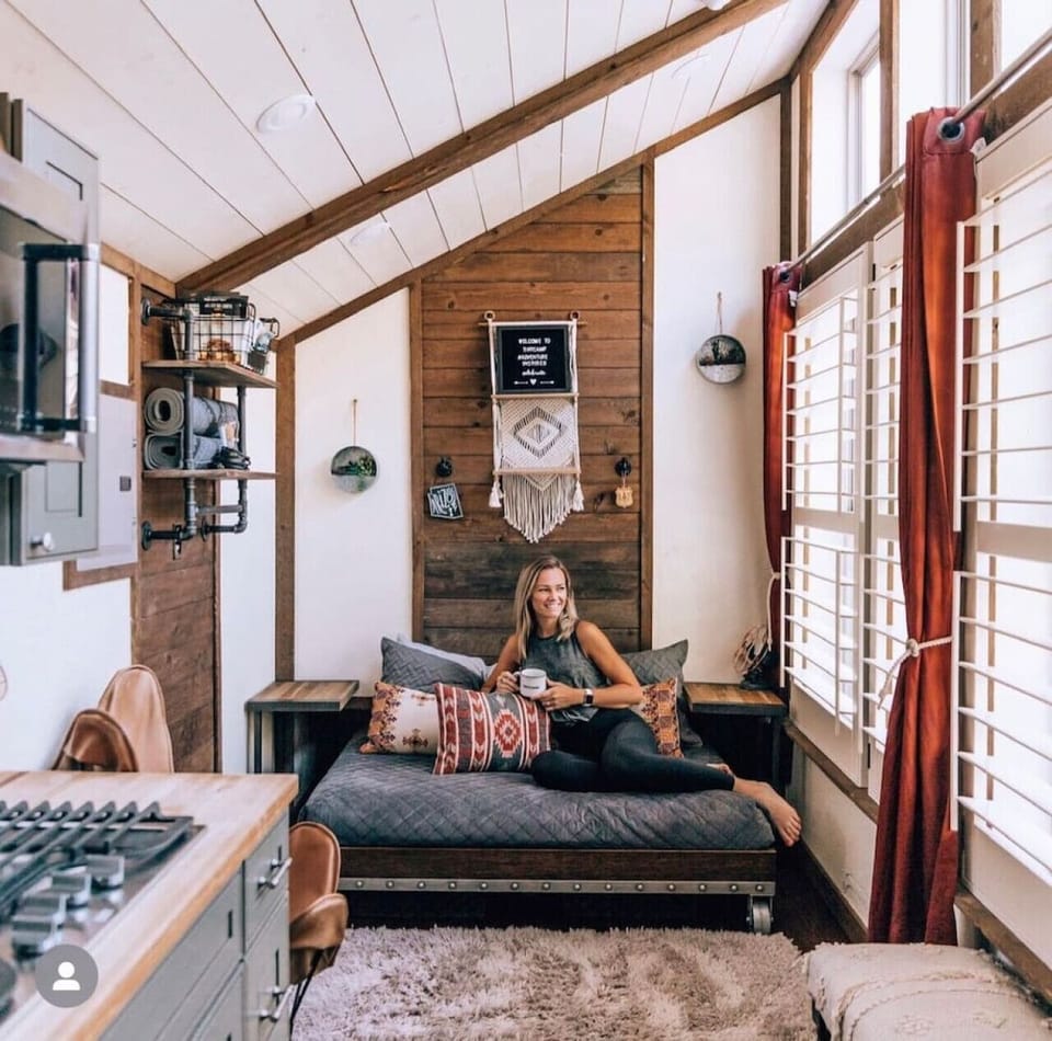 Bright and thoughtfully designed tiny home with soaring ceilings, oversized windows, a comfortable lounge, and a fully equipped kitchenette. The perfect retreat for couples seeking comfort, style, and relaxation.