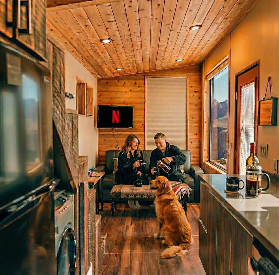 Relax inside your thoughtfully designed tiny home featuring comfortable seating, Smart TV with Netflix, full kitchen, washer and dryer, and warm modern finishes.