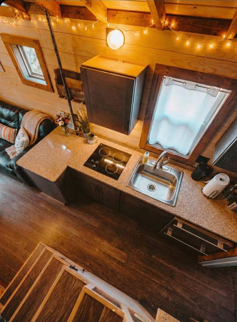 Compact kitchenette with stovetop, sink, and string lights overhead.