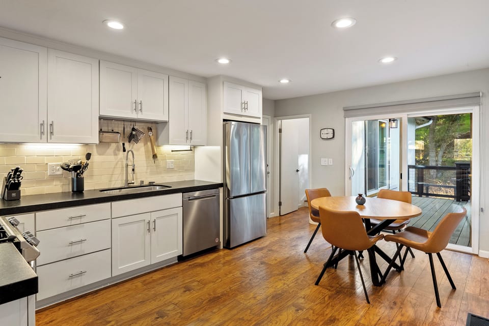 Gather for a meal in this beautiful open-concept dining area, featuring stylish tan leather seating and a warm wooden table. The modern kitchen and direct access to the outdoor deck make this the perfect space for entertaining and enjoying the fresh air.