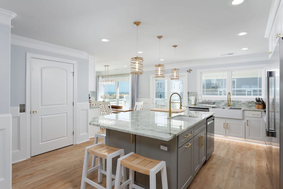 3rd floor kitchen area features two tables and seating around the island 