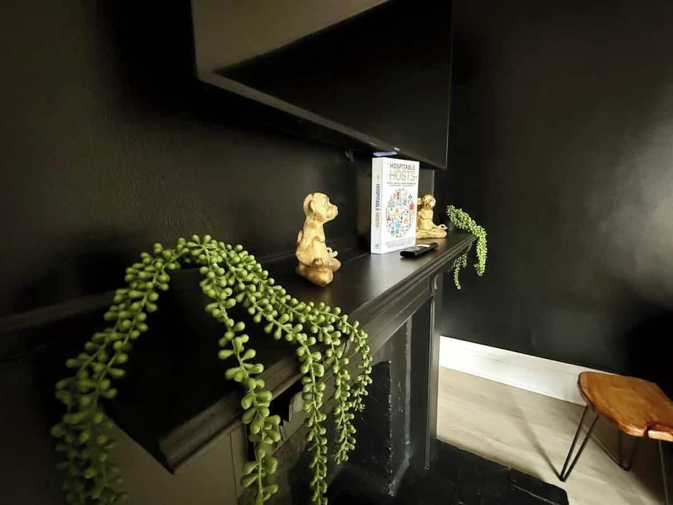 Host memorable gatherings in our stylish dining area at Jungle House Airbnb, featuring a sleek wooden table, vibrant yellow chairs, and a lush green accent wall  The perfect blend of modern elegance and cozy charm in Short North Columbus