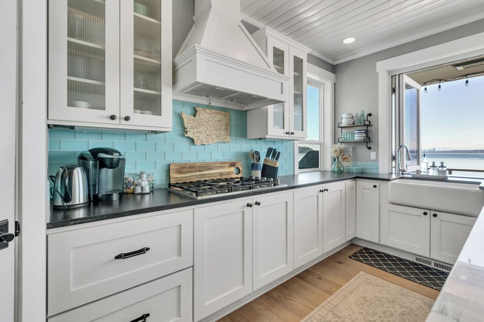 Bright coastal kitchen with farmhouse sink and serene water views