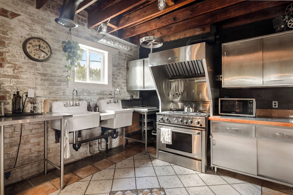 Commercial grade kitchen, including 6 burner gas stove and double sinks.