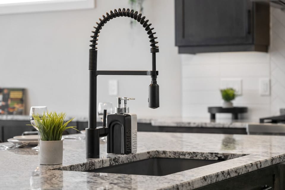 Modern kitchen with black pull-down faucet, granite countertops, and stainless steel appliances
