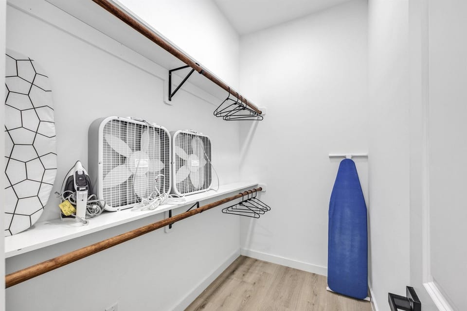 Fully equipped walk-in primary closet featuring two portable fans.