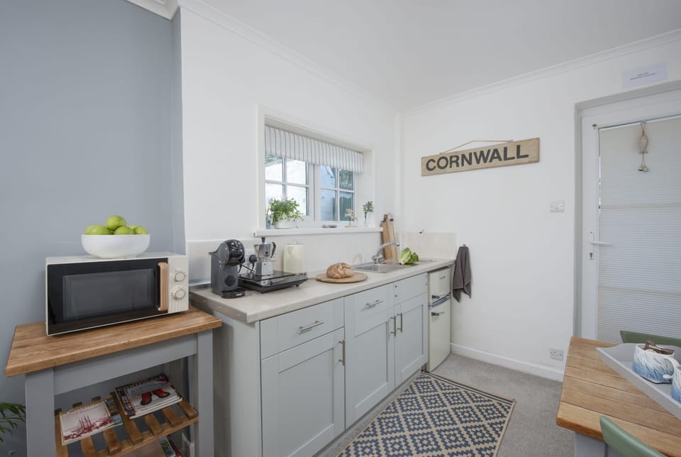 Kitchen with electric hot plate, microwave, fridge freezer, kettle, toaster, Nespresso coffee machine and a range of pans and utensils - Olive Cottage by Stay Ca Holidays
