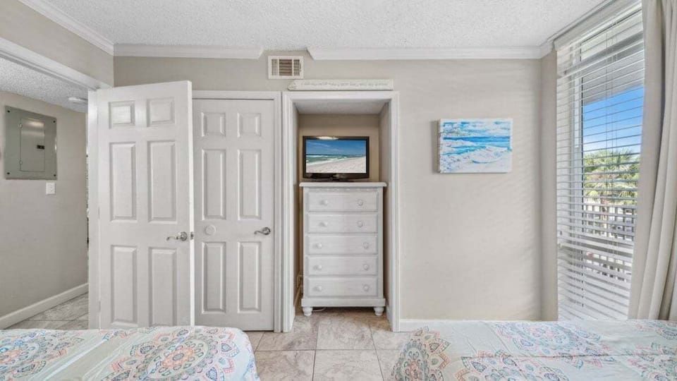 The guest bedroom features a built-in dresser, TV, and natural light for a bright, comfortable space.