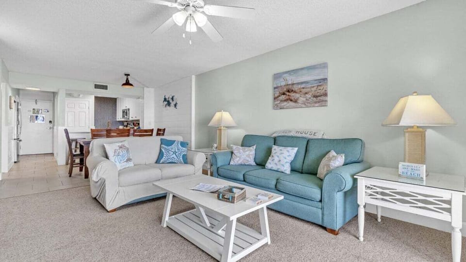This inviting living space features soft blues, plush seating, and coastal decor for relaxing after a day at the beach.
