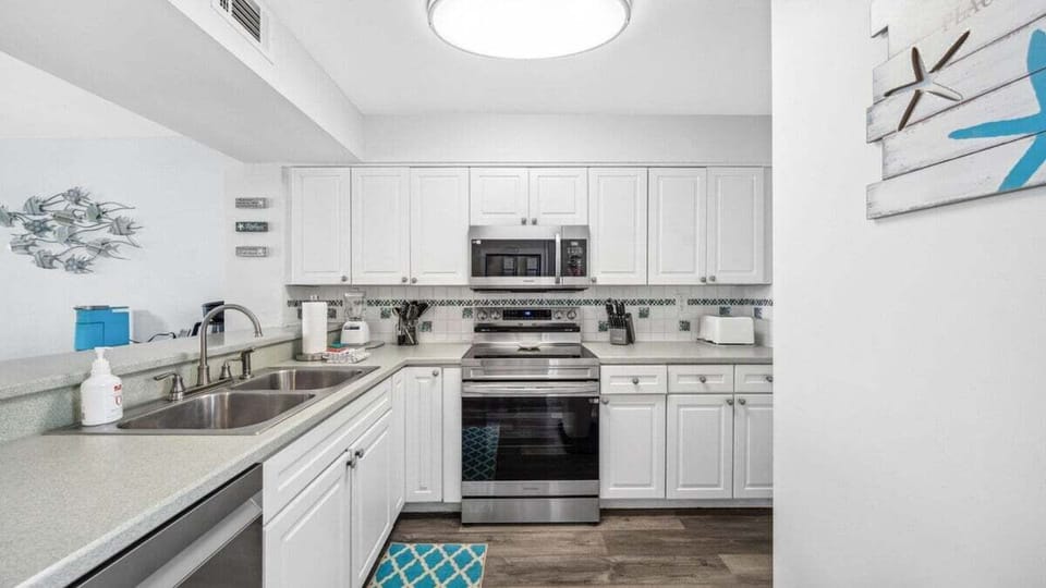 This fully equipped kitchen features stainless steel appliances, ample cabinet space, and a double sink—perfect for home-cooked meals by the beach. Bright, clean, and ready for your stay.