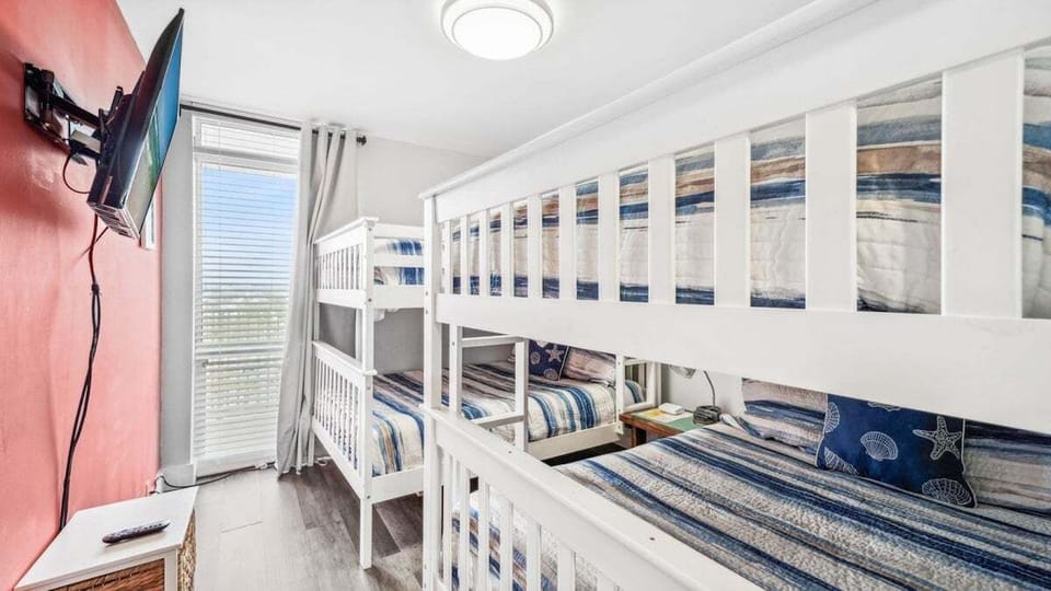 This fun bunk room features two twin-over-twin bunk beds with coastal bedding and a wall-mounted TV—perfect for kids or extra guests to relax and unwind.