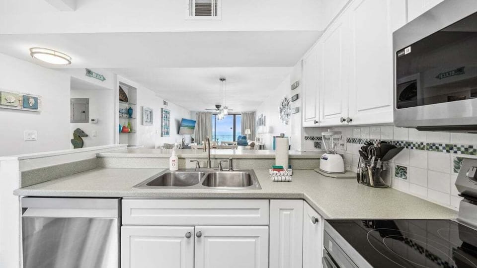 Enjoy Gulf views right from the kitchen in this open-concept layout, featuring stainless steel appliances and a spacious breakfast bar. Perfect for cooking while staying connected with the rest of the living space.