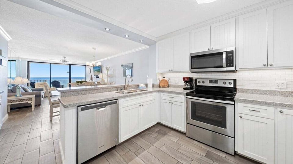 Fully equipped kitchen with stainless steel appliances and view of the dining and living areas.