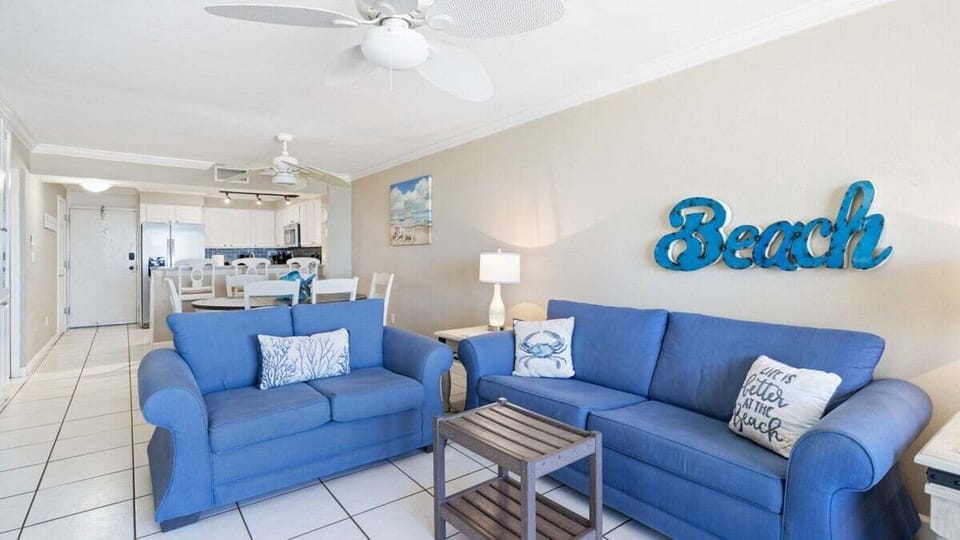 Living Room. Cozy and coastal with vibrant blue sofas, charming beach décor, and plenty of natural light—perfect for relaxing after a day in the sun.