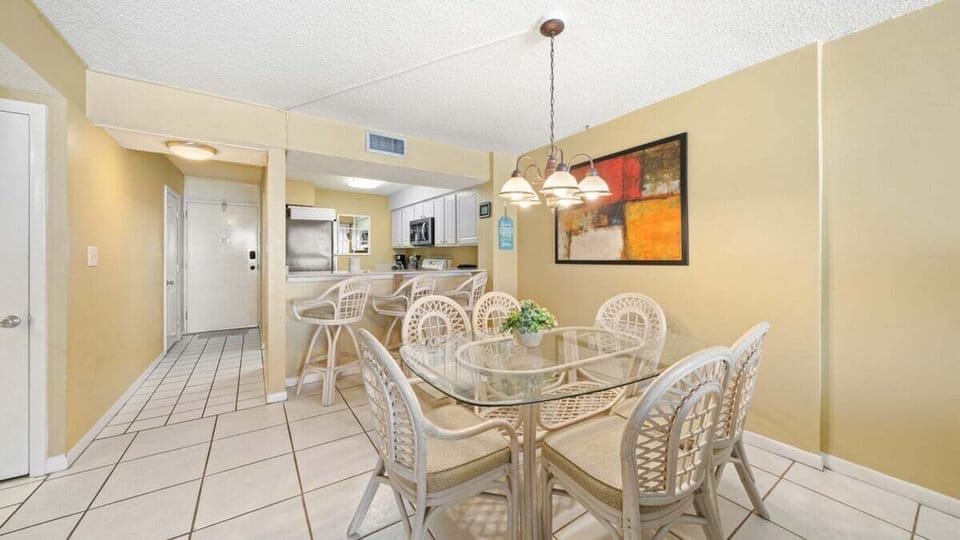 Spacious Dining Area. Gather around the elegant glass-top table with seating for six, plus four barstools at the breakfast bar—plenty of room for meals, games, or planning your beach adventures.