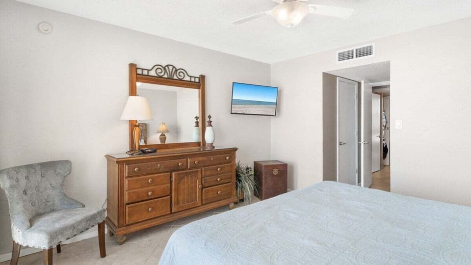 Primary bedroom with dresser, mounted TV, and coastal charm.